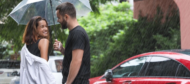 Couple with umbrella under the rain in the city. Cheap Mexican car insurance