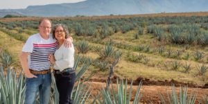 Retired couple in front of agave fields. Cheap Mexican auto insurance.
