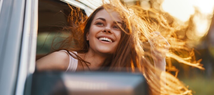Happy young woman with flowing hair enjoying a summer road trip. Mexican car insurance
