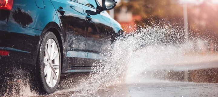 Coche circulando por un charco y salpicando agua. Aseguranza para Mexico