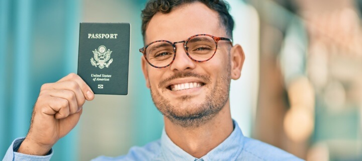 Joven con su pasaporte americano en mano. Aseguranza de auto para Mexico.