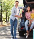 Familia feliz junto al coche en un día soleado. Viaje por carretera a Mexico. Aseguranza de auto para Mexico.