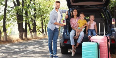 Familia feliz junto al coche en un día soleado. Viaje por carretera a Mexico. Aseguranza de auto para Mexico.