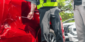 Ajustador de seguros en escena del accidente apuntando a un golpe en el auto. Seguro de Auto para Mexico.