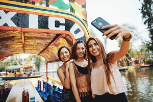 girls taking selfie in front of mexico sign