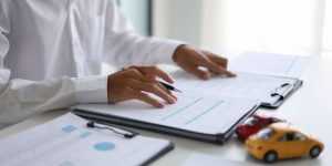 Driving a financed vehicle in Mexico. A man signing a contract for a car loan, lease, vehicle registration and insurance policy. Cheap Mexican Car Insurance.